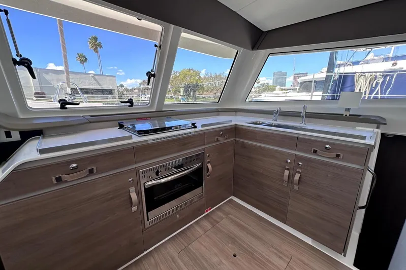 Wiley Pixie Yacht Photos Pics Modern kitchen interior of 2023 Bali CATSPACE yacht with sleek wood cabinetry and large windows.