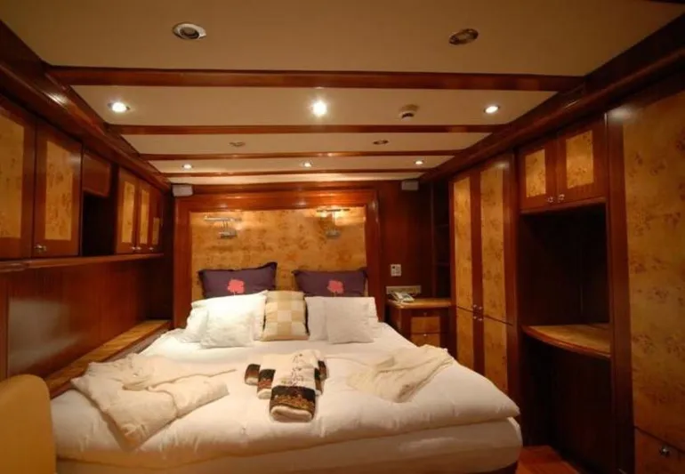 42 M Custom Made Motorsailor Yacht Photos Pics Luxurious bedroom interior of 2006 Custom Made 42 M Motorsailor with wood paneling and cozy bedding.