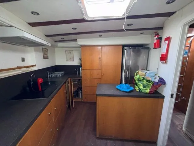 42 M Custom Made Motorsailor Yacht Photos Pics Spacious kitchen in 2006 Custom Made 42 M Motorsailor with modern appliances and wooden cabinetry.