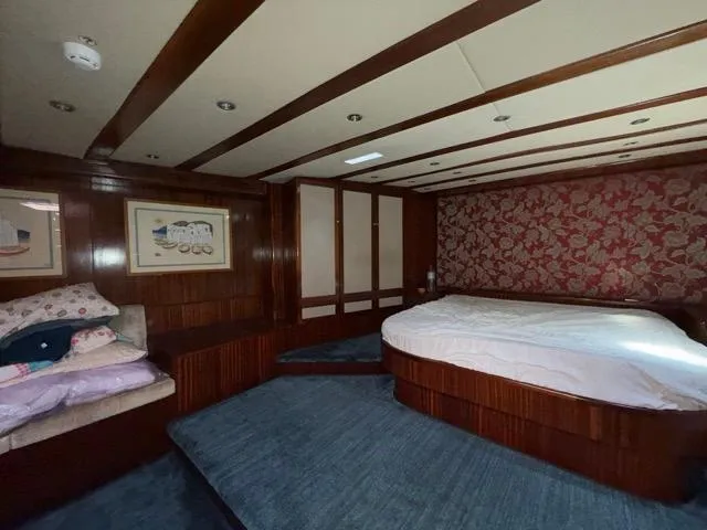 42 M Custom Made Motorsailor Yacht Photos Pics Luxurious bedroom interior of 2006 Custom Made 42 M Motorsailor with wood paneling and floral wallpaper.