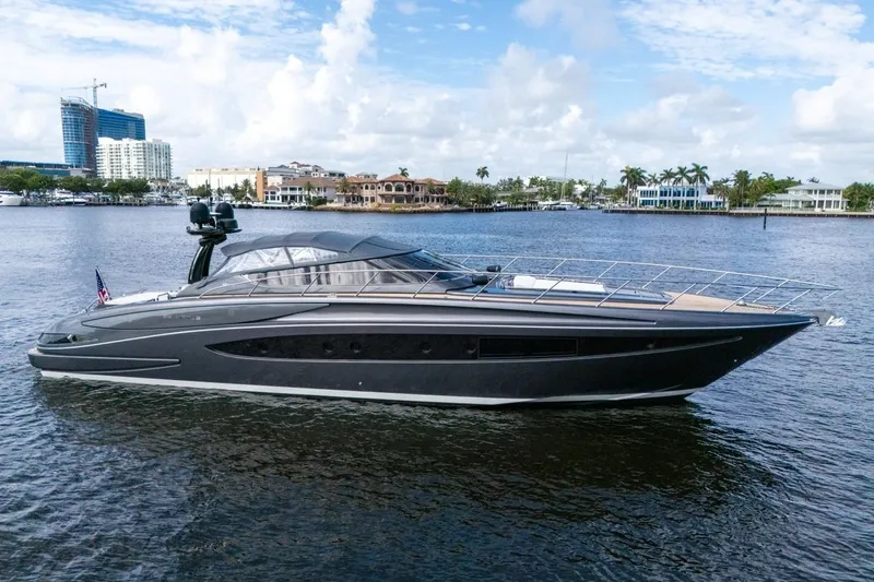  Yacht Photos Pics Luxurious 2015 Riva 63 yacht cruising on a serene waterfront with cityscape backdrop.