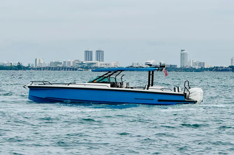 Out Of The Blue Yacht Photos Pics 2021 Axopar 37 Sun Top boat cruising on water with city skyline backdrop.