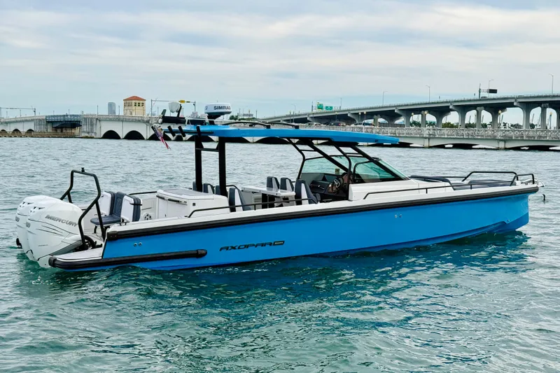 Out Of The Blue Yacht Photos Pics 2021 Axopar 37 Sun Top boat on water near a bridge, featuring sleek blue design.