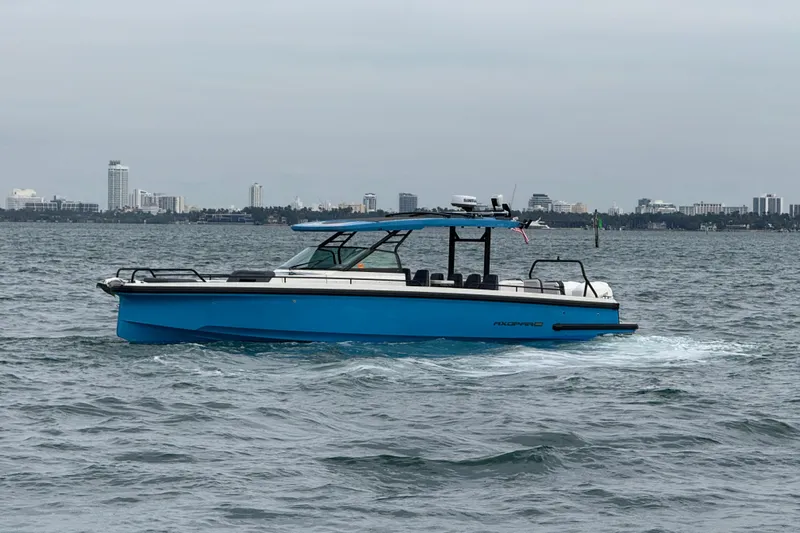 Out Of The Blue Yacht Photos Pics 2021 Axopar 37 Sun Top boat cruising on water with city skyline in background.