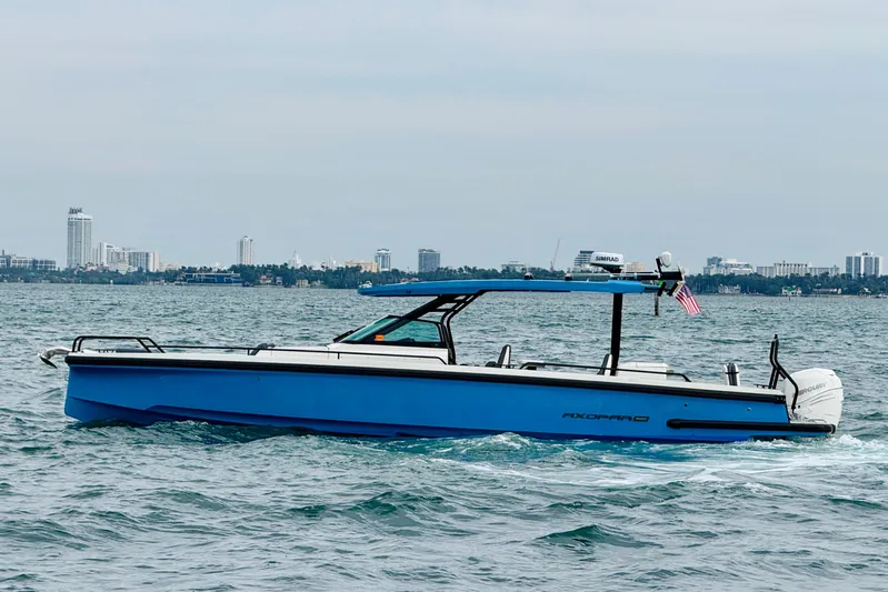 Out Of The Blue Yacht Photos Pics 2021 Axopar 37 Sun Top boat cruising on water with city skyline in background.
