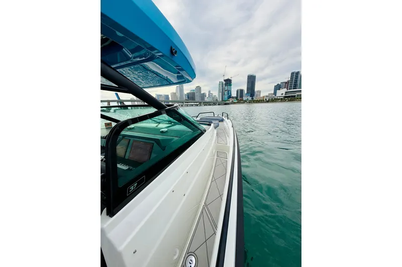 Out Of The Blue Yacht Photos Pics 2021 Axopar 37 Sun Top boat cruising near city skyline on calm water.