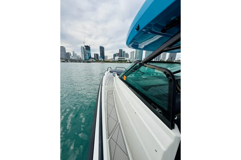 Out Of The Blue Yacht Photos Pics Axopar 37 Sun Top 2021 cruising near city skyline on a cloudy day.