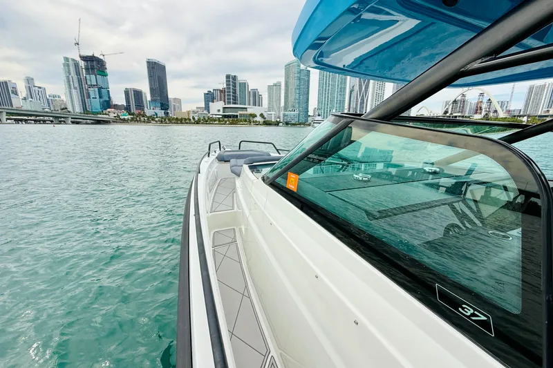 Out Of The Blue Yacht Photos Pics 2021 Axopar 37 Sun Top boat cruising near city skyline on calm water.