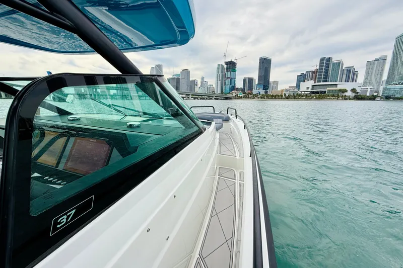 Out Of The Blue Yacht Photos Pics 2021 Axopar 37 Sun Top boat cruising near city skyline.