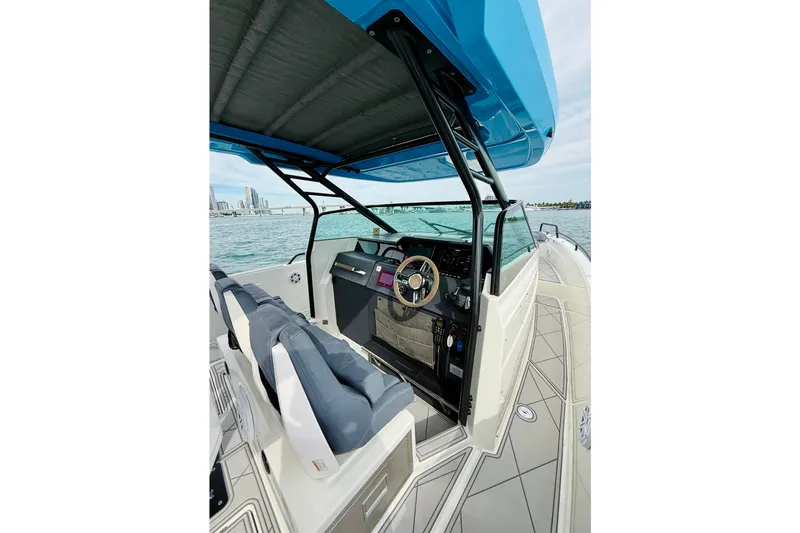 Out Of The Blue Yacht Photos Pics 2021 Axopar 37 Sun Top boat interior with helm, blue canopy, and ocean view.