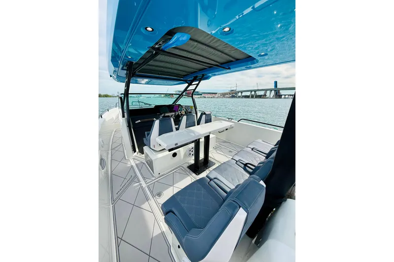 Out Of The Blue Yacht Photos Pics 2021 Axopar 37 Sun Top boat interior with seating and table, overlooking water and bridge.