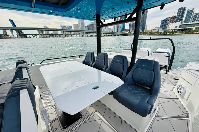 Out Of The Blue Yacht Photos Pics 2021 Axopar 37 Sun Top boat interior with seating and table, city skyline view.