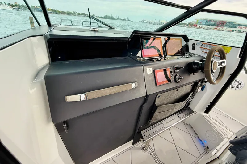 Out Of The Blue Yacht Photos Pics 2021 Axopar 37 Sun Top helm with modern controls and navigation screens, docked by the water.