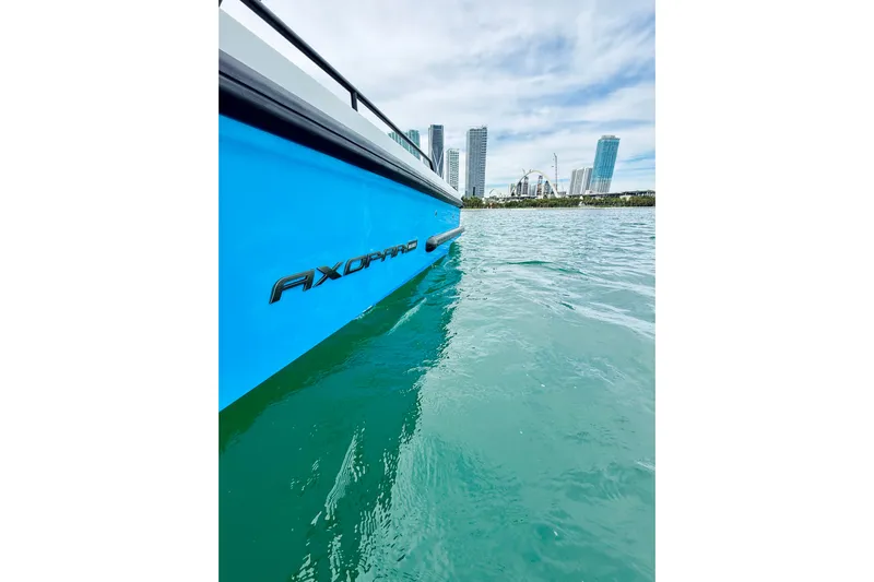 Out Of The Blue Yacht Photos Pics 2021 Axopar 37 Sun Top boat on turquoise water with city skyline background.