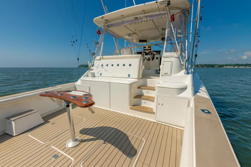 Alexa Corinne Yacht Photos Pics 1999 Ocean Yachts 48 Express boat deck with fishing setup on calm water.