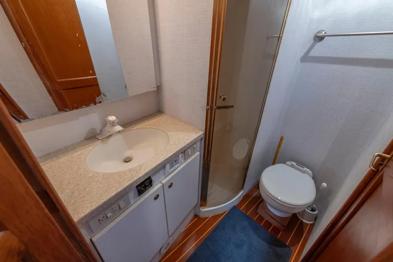 Alexa Corinne Yacht Photos Pics Bathroom interior of 1999 Ocean Yachts 48 Express, featuring sink, shower, and toilet.