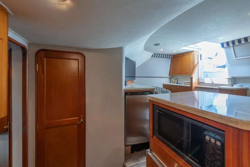 Alexa Corinne Yacht Photos Pics Interior of 1999 Ocean Yachts 48 Express, featuring kitchen area with microwave and wooden cabinetry.