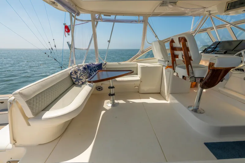 Alexa Corinne Yacht Photos Pics 1999 Ocean Yachts 48 Express interior with seating, table, and helm, overlooking the ocean.