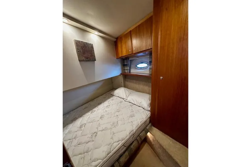  Yacht Photos Pics Cozy bedroom in 2001 Silverton 42 Convertible yacht with wooden cabinets and porthole.