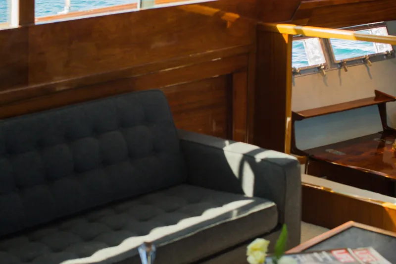 New School Yacht Photos Pics Interior of 1966 Chris-Craft Constellation yacht with wooden paneling and a gray sofa.