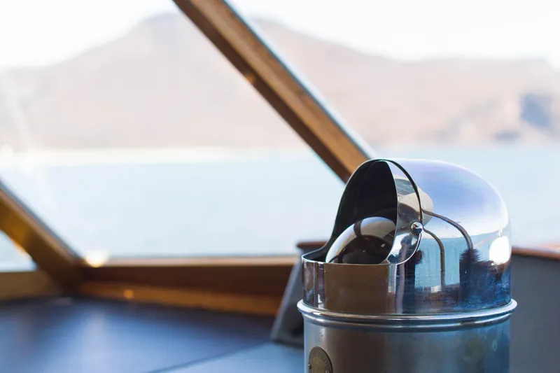 New School Yacht Photos Pics 1966 Chris-Craft Constellation interior with a polished metal compass, scenic mountain view.
