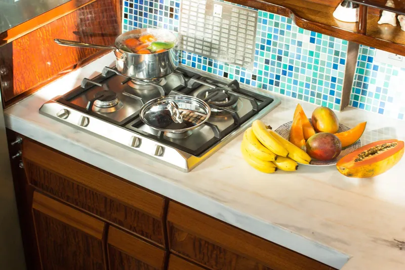 New School Yacht Photos Pics 1966 Chris-Craft Constellation kitchen with stove, fruit, and colorful tile backsplash.