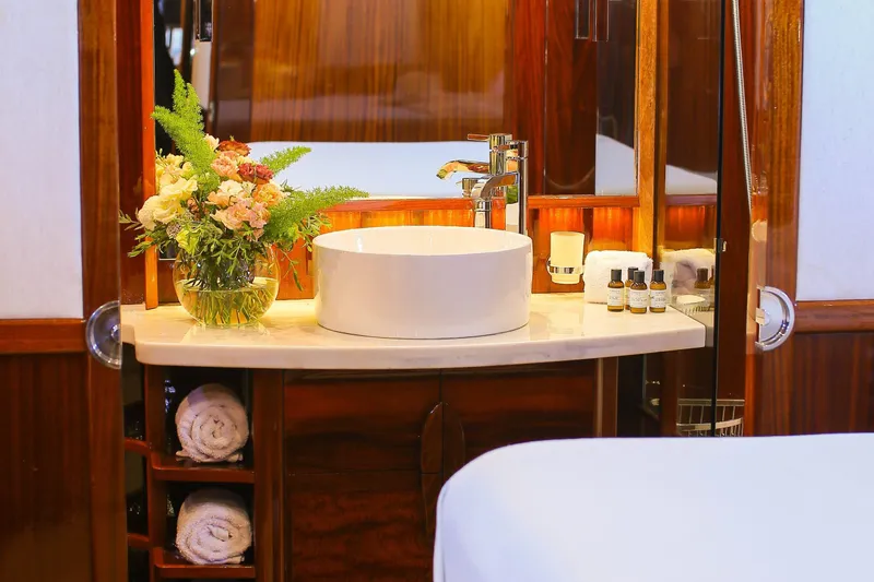 New School Yacht Photos Pics Luxurious bathroom on 1966 Chris-Craft Constellation yacht with elegant sink and floral arrangement.