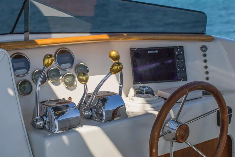 New School Yacht Photos Pics 1966 Chris-Craft Constellation helm with chrome controls, wooden steering wheel, and navigation instruments.