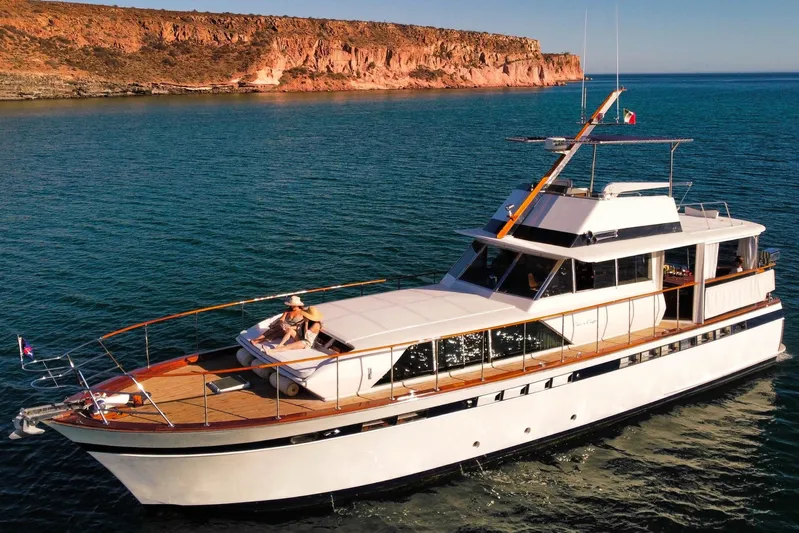 New School Yacht Photos Pics 1966 Chris-Craft Constellation yacht cruising near rocky coastline in clear blue waters.
