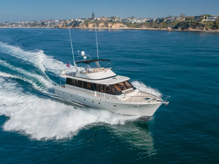 Artemis Yacht Photos Pics 1996 Offshore Yachts Pilothouse cruising on open water near a scenic coastline.