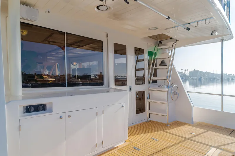 Artemis Yacht Photos Pics 1996 Offshore Yachts Pilothouse deck with wooden flooring and stairs, overlooking serene water.