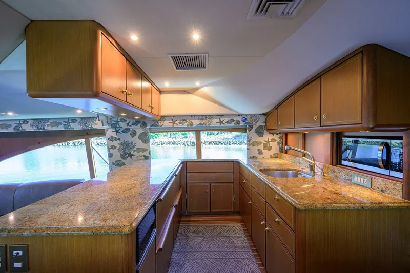 Hook'em Dan O Yacht Photos Pics Luxurious kitchen interior of 2006 Ocean Yachts 57 Super Sport with wood cabinets and granite countertops.