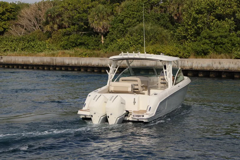  Yacht Photos Pics 2021 Boston Whaler 320 Vantage cruising on water near lush greenery.