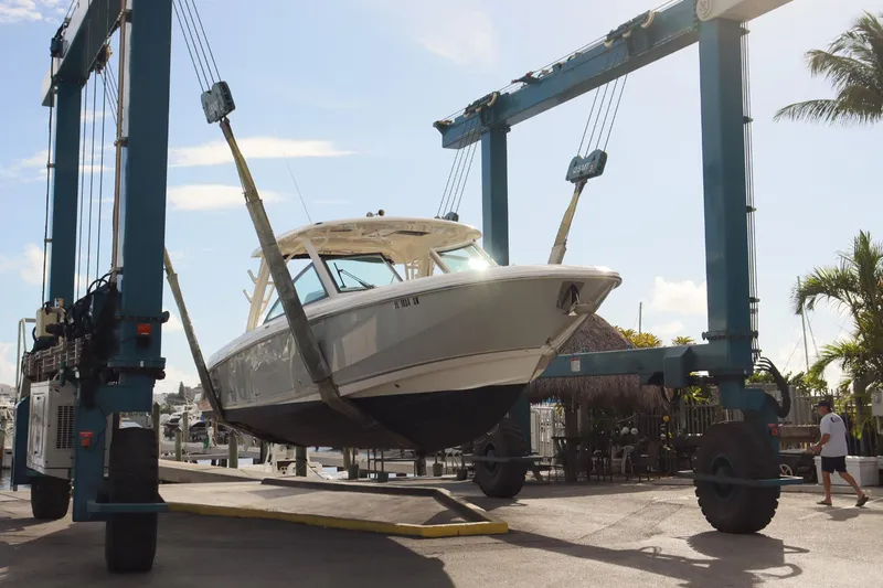  Yacht Photos Pics 2021 Boston Whaler 320 Vantage boat being lifted at a marina with blue sky background.