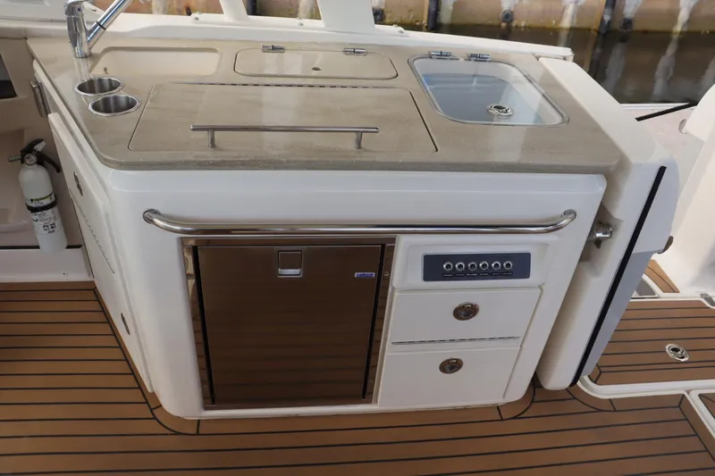  Yacht Photos Pics 2021 Boston Whaler 320 Vantage boat kitchen with sink, storage, and wooden flooring.