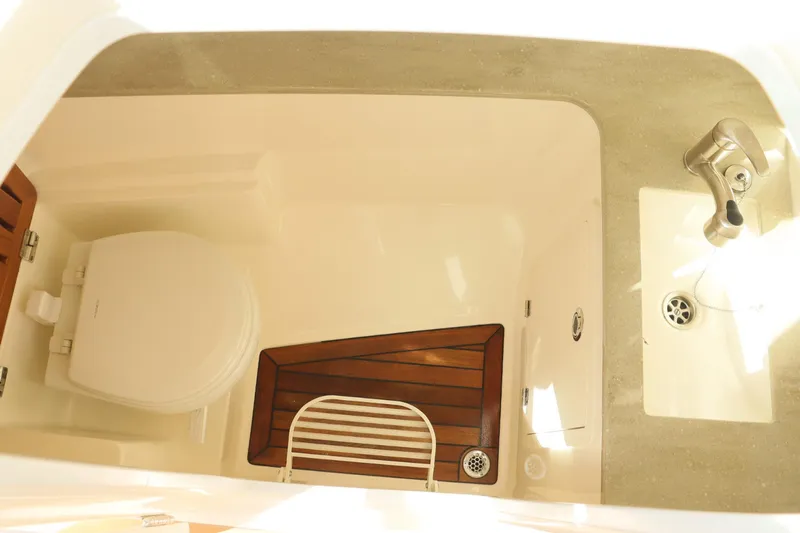  Yacht Photos Pics 2021 Boston Whaler 320 Vantage boat bathroom with toilet, sink, and wooden floor mat.