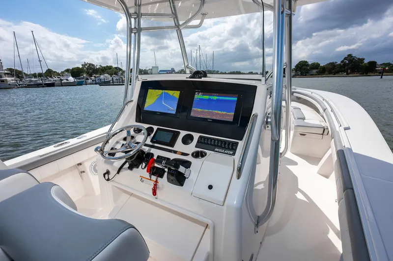 Dauntless Yacht Photos Pics 2018 Regulator 34 FS boat cockpit with navigation screens and steering wheel, docked by the marina.