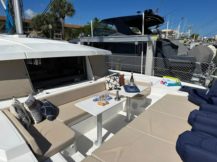 Encore Yacht Photos Pics Luxurious Bali 4.1 catamaran deck with seating, table, and nautical decor, docked at marina.