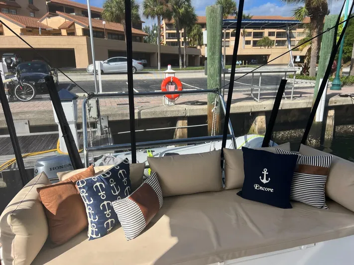 Encore Yacht Photos Pics Cozy boat seating with nautical-themed pillows, docked near waterfront buildings.