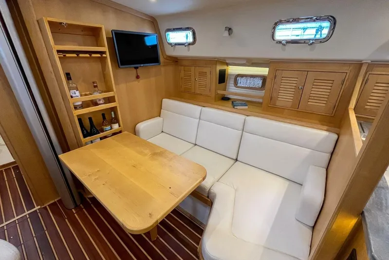  Yacht Photos Pics Cozy interior of 2023 Island Packet 439 yacht with white seating and wooden table.
