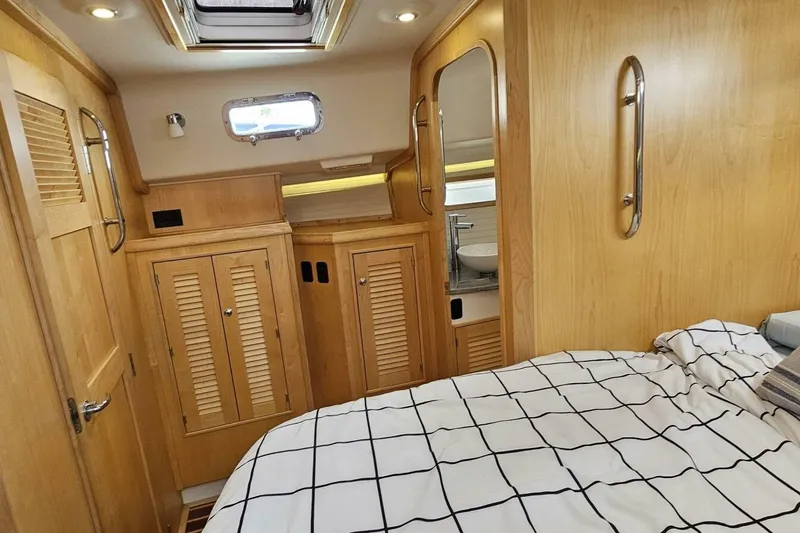  Yacht Photos Pics 2023 Island Packet 439 yacht interior with wooden cabinetry and cozy bedding.