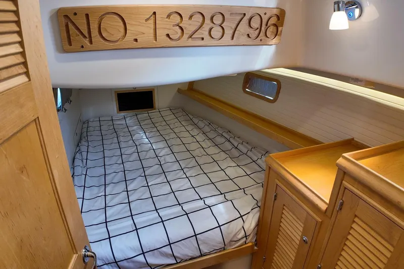 Yacht Photos Pics Cozy cabin interior of 2023 Island Packet 439 sailboat with bed and wooden cabinetry.