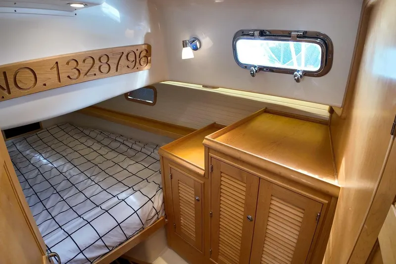  Yacht Photos Pics 2023 Island Packet 439 cabin interior with bed, wooden cabinetry, and porthole window.