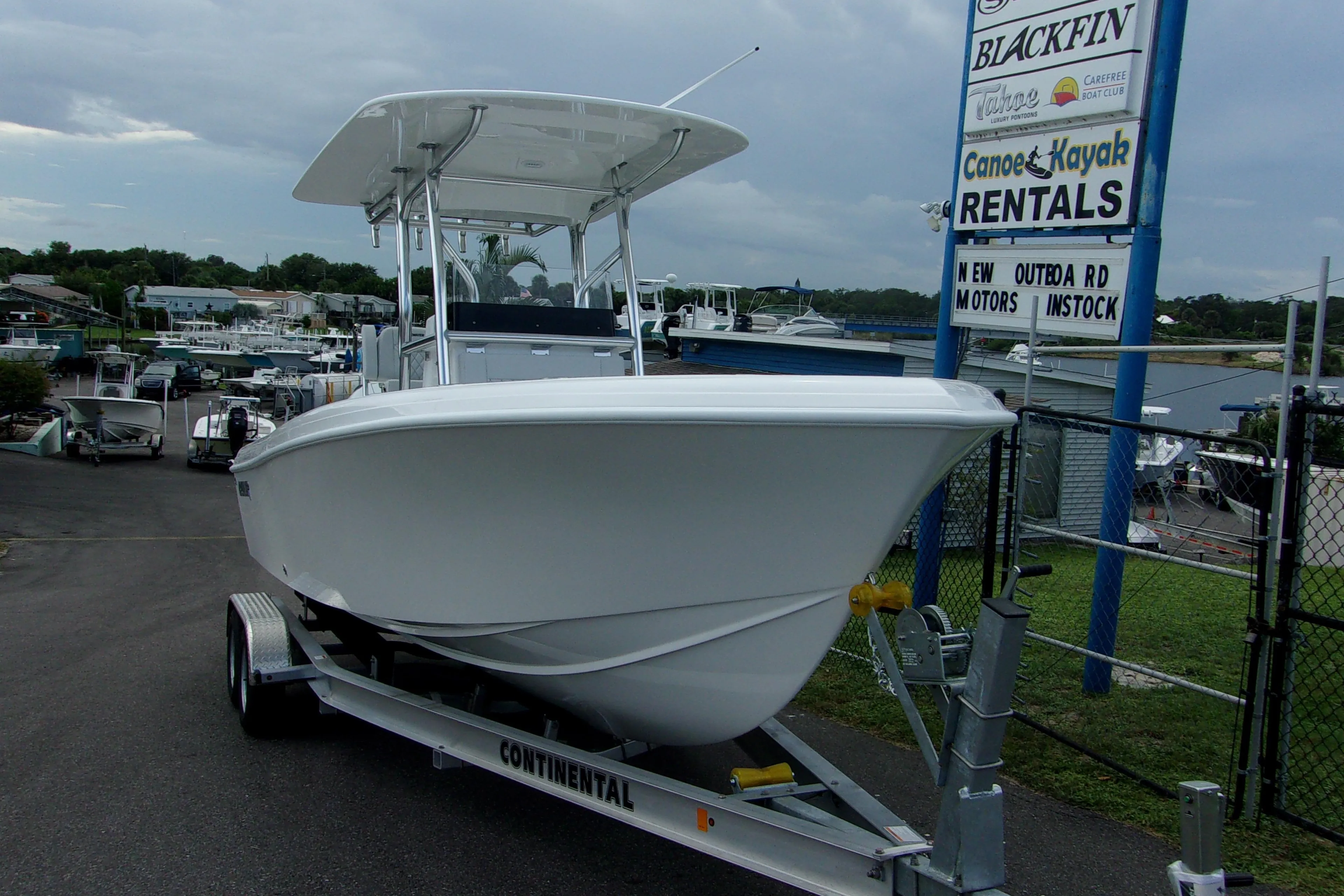 2025 Bluewater 23 T boat on trailer at rental facility, overcast sky.