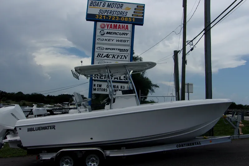  Yacht Photos Pics 2025 Bluewater 23 T boat on trailer at dealership, cloudy sky background.