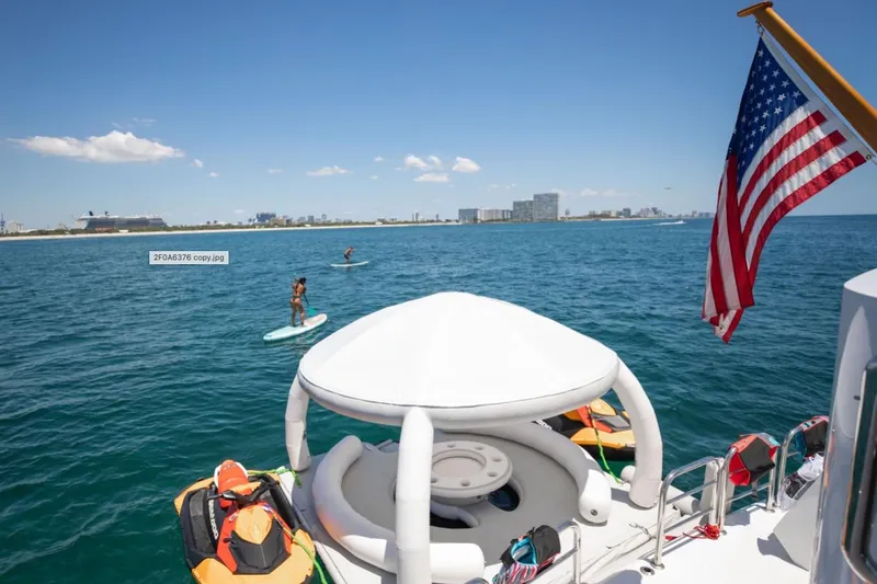 Carpe Diem Yacht Photos Pics Luxury yacht Intermarine RPH 95, 2001, with paddleboarders and American flag on open sea.