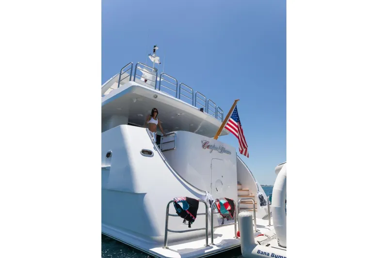 Carpe Diem Yacht Photos Pics 2001 Intermarine RPH 95 yacht with American flag, woman on deck, clear blue sky.