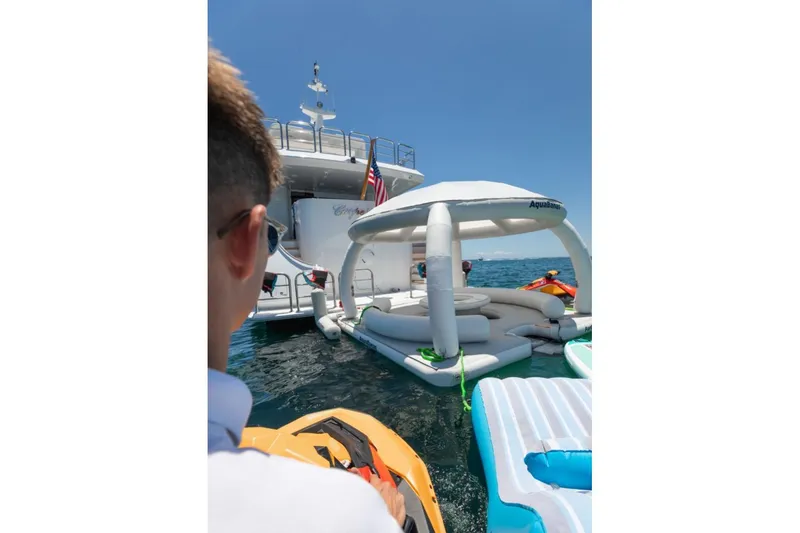 Carpe Diem Yacht Photos Pics Person on jet ski near Intermarine RPH 95 yacht with inflatable water lounge, 2001 model.