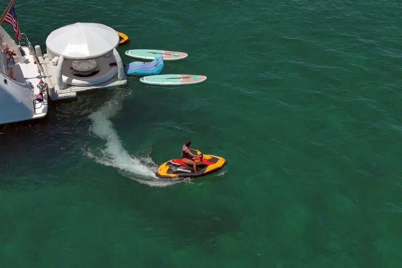 Carpe Diem Yacht Photos Pics Jet ski near 2001 Intermarine RPH 95 yacht with paddleboards and inflatable dock in clear water.