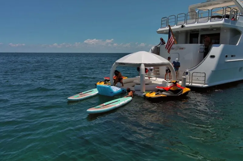 Carpe Diem Yacht Photos Pics Luxury yacht Intermarine RPH 95 with water sports equipment and floating lounge, ocean backdrop.